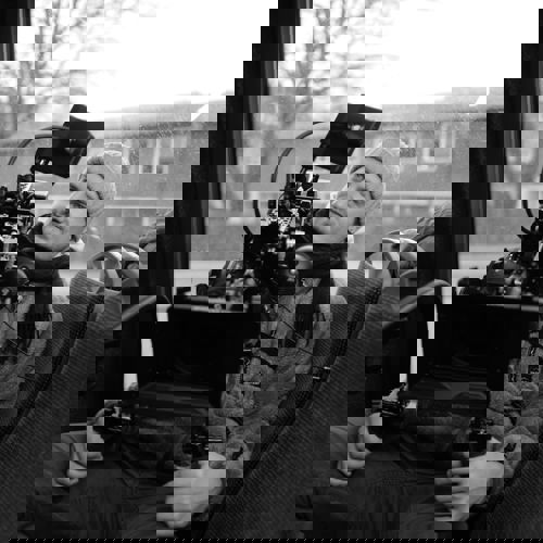 Photografer sitting in a bus shooting a film with his camera